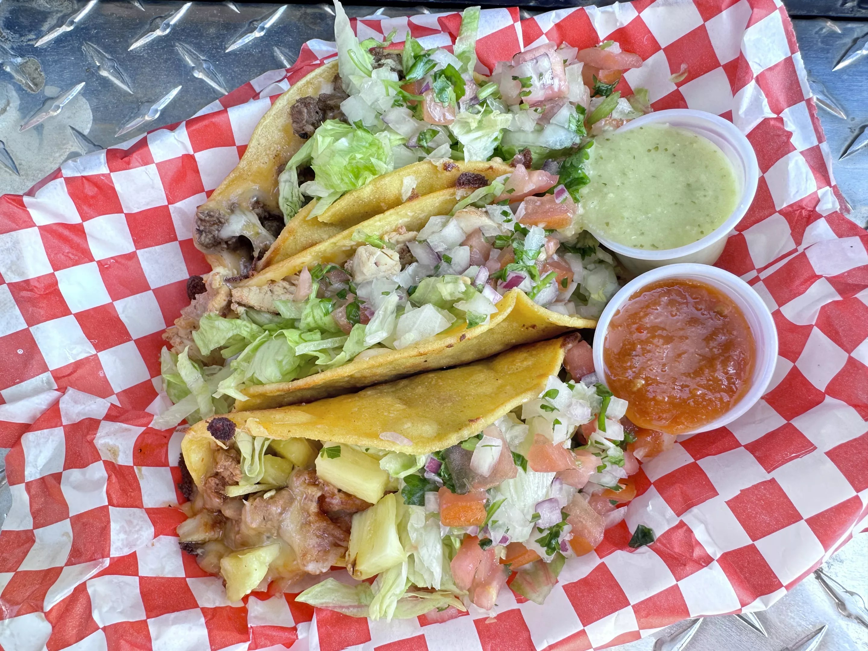 three tacos with cups of salsa