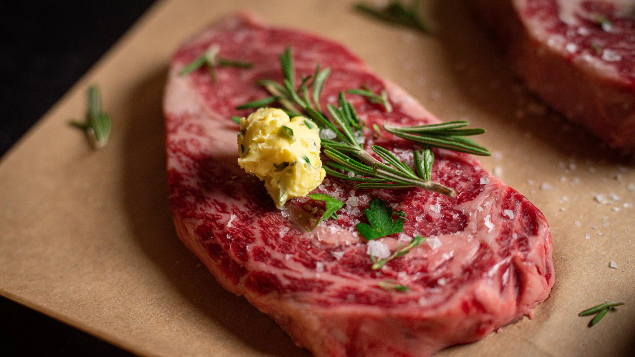 a raw steak with butter and rosemary on top