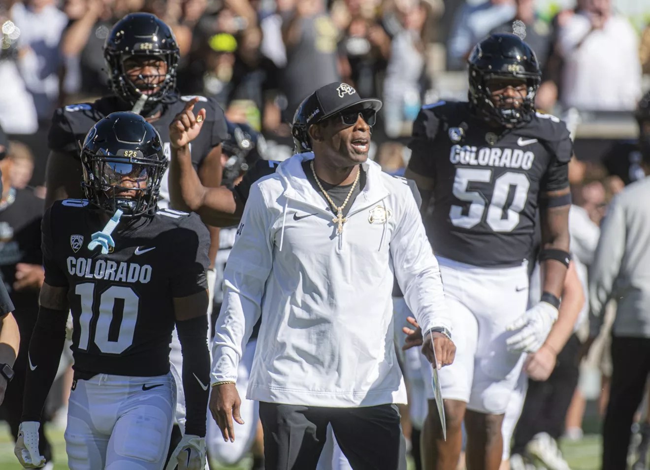 CU football coach Deion Sanders surrounded by Buffalo football players.