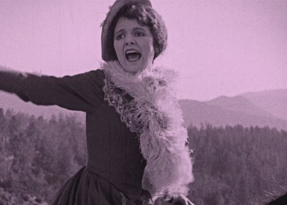 woman throws out her arms yelling with a cat hanging from her neck