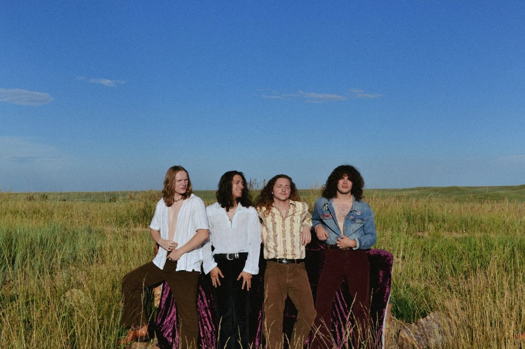 four men standing in a field under blue skies