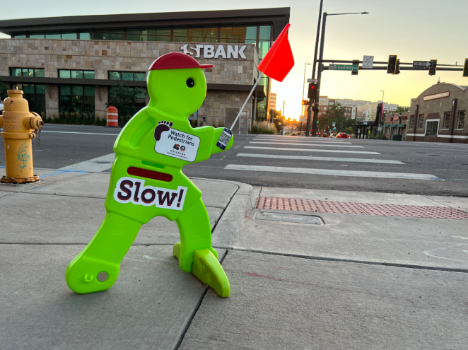 A green plastic boy with a red hat and a sign that says "slow" on his stomach.