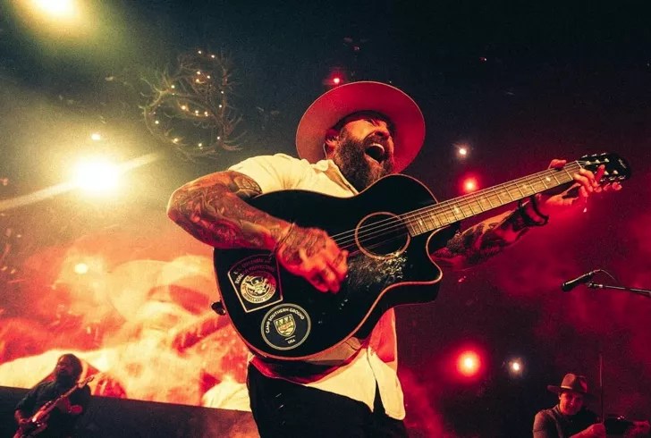 man wearing cowboy hat smiling and playing guitar