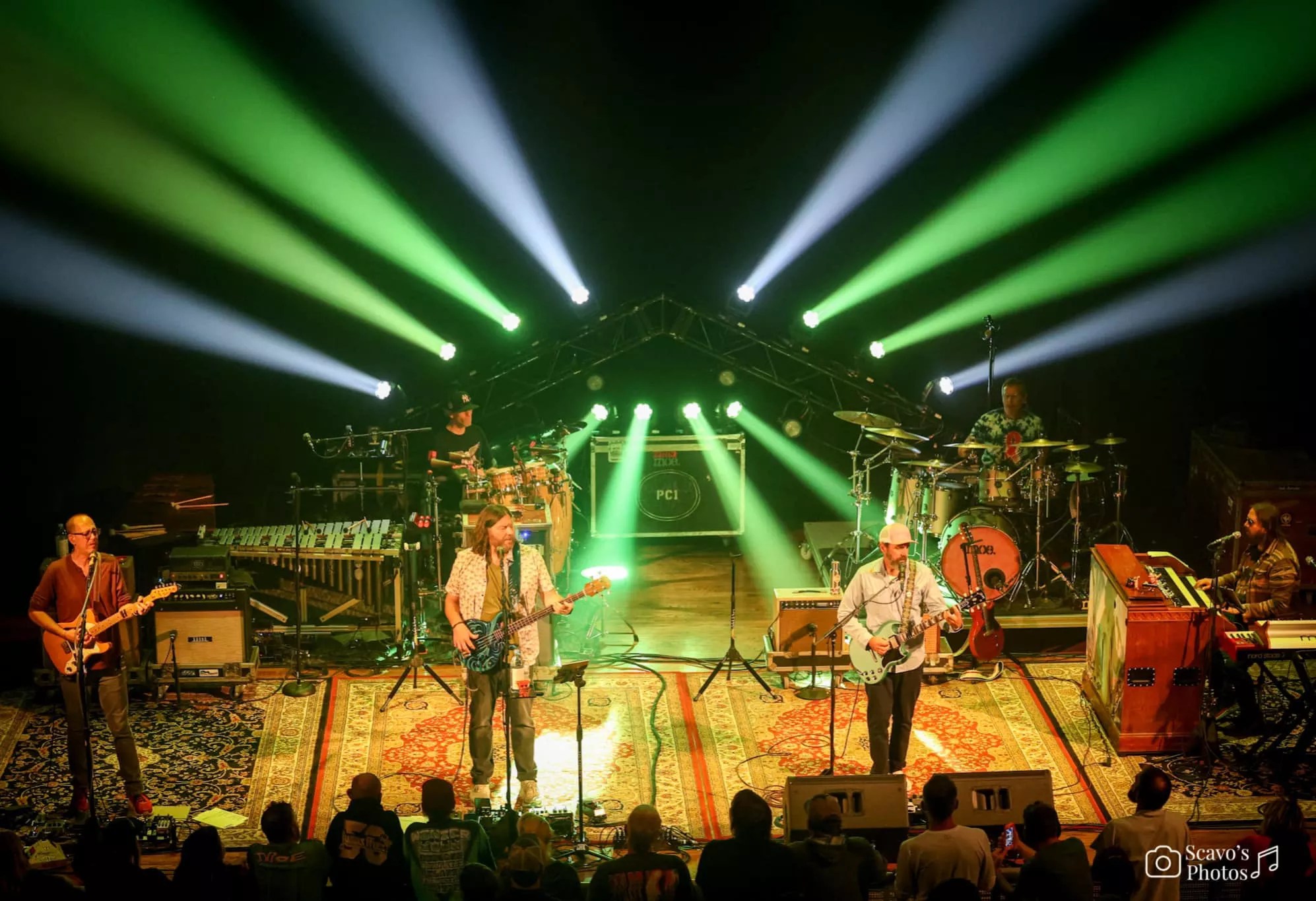 band playing on stage with green and silver and orange lights.