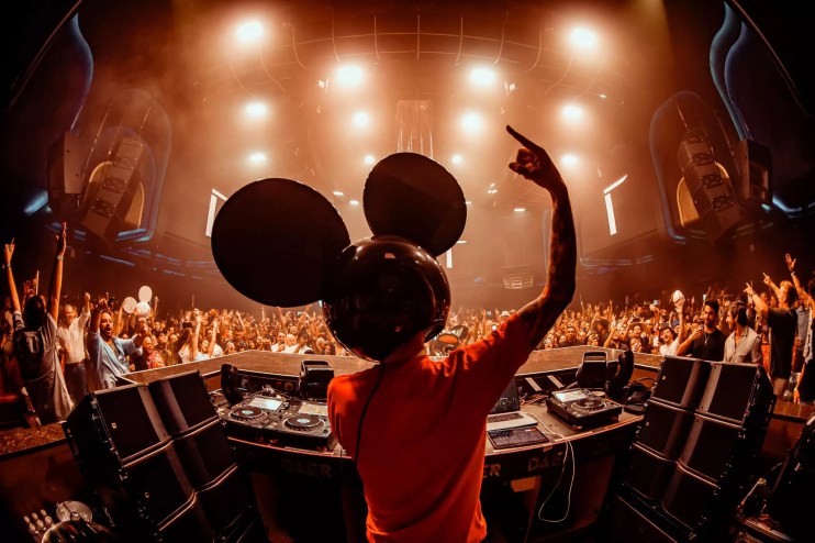man with mouse mask on his head deejays to an audience