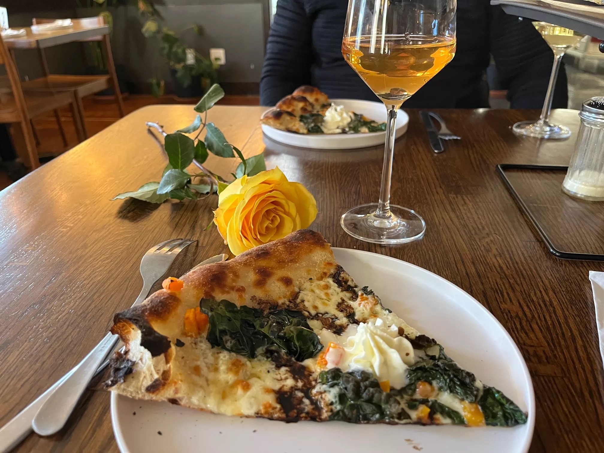 slice of pizza, glass of wine and a yellow rose