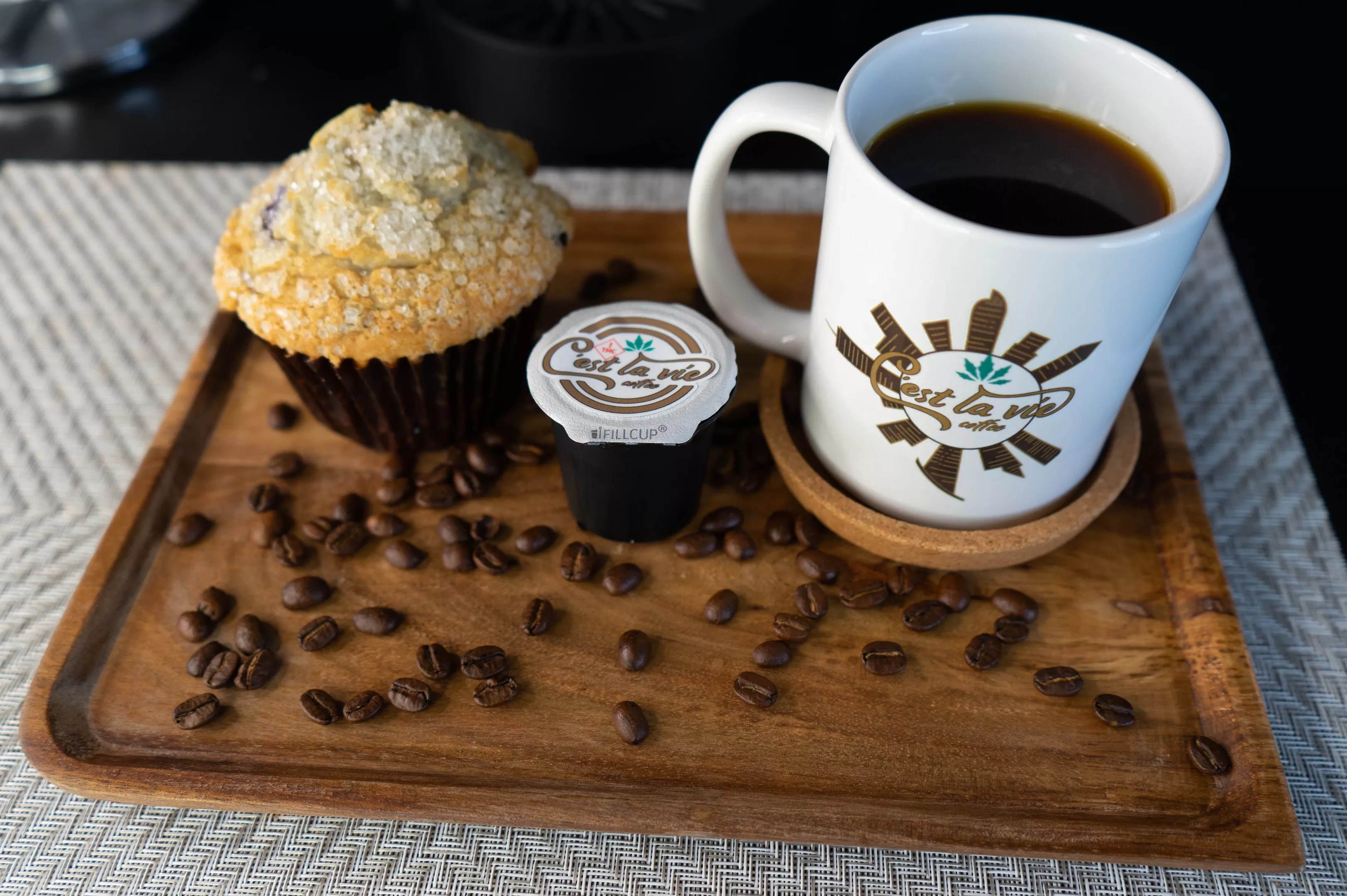 Weed-infused coffee pods, coffee beans, a cup of THC coffee and a muffin.