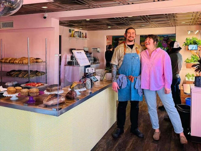 man in an apron posing with woman in pink shirt