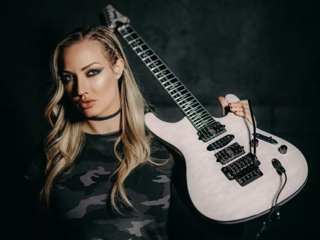 woman resting a white electric guitar on her shoulder