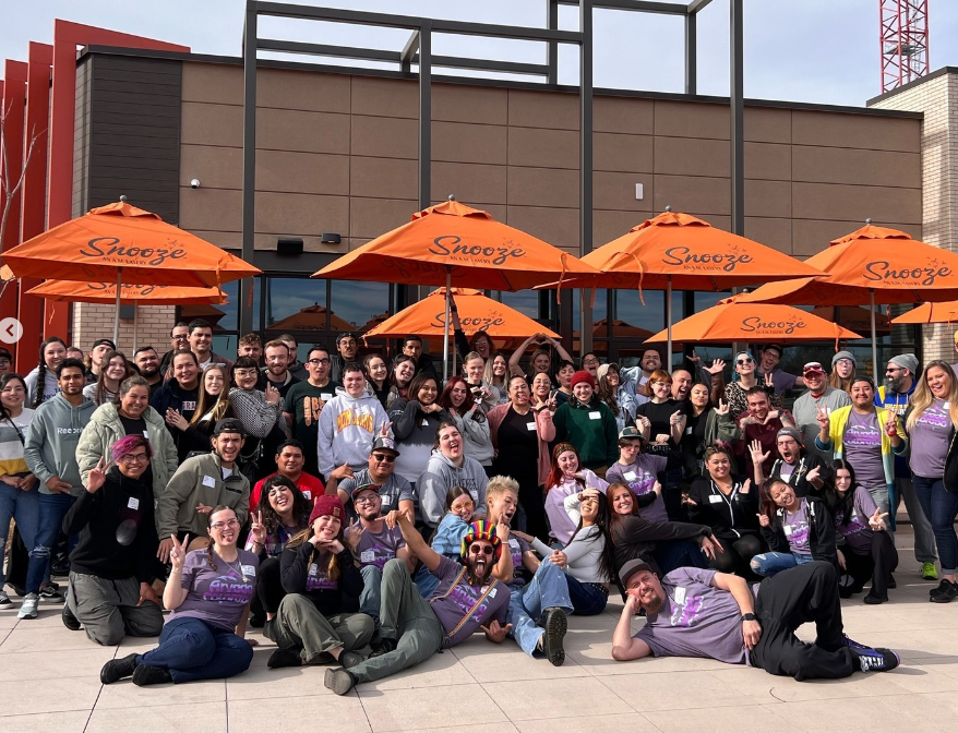 a large group of people in front of orange umbrellas