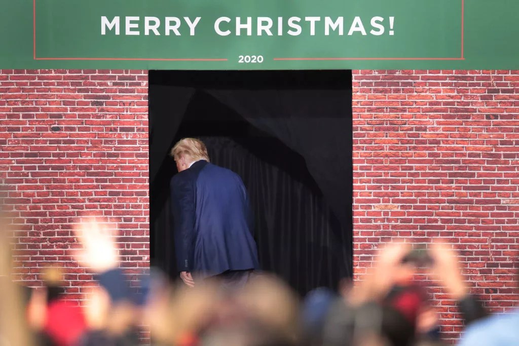 trump exiting through door with Merry Christmas sign