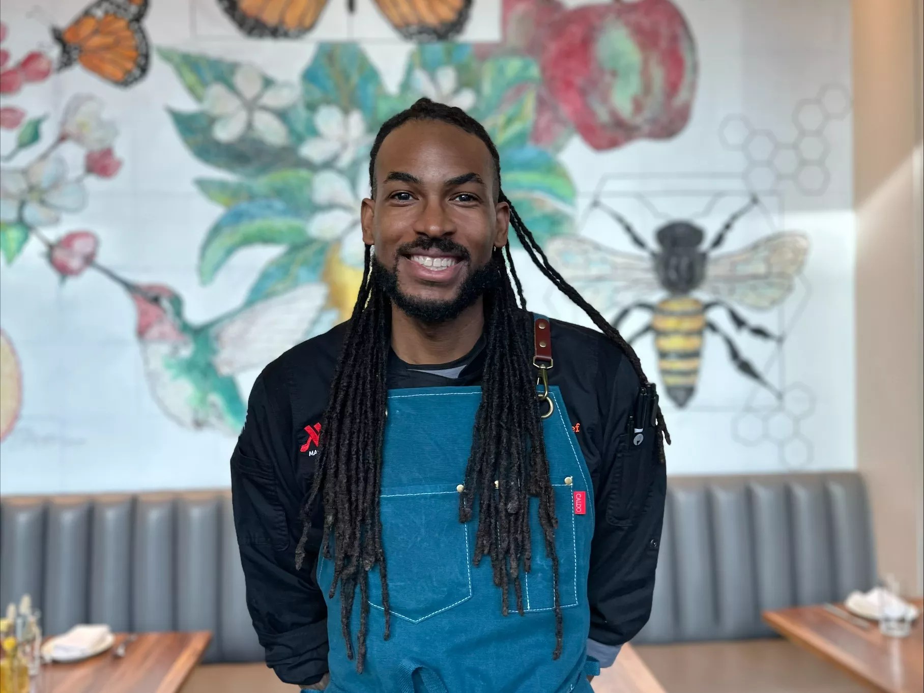 a man standing in front of a mural with flowers and bees