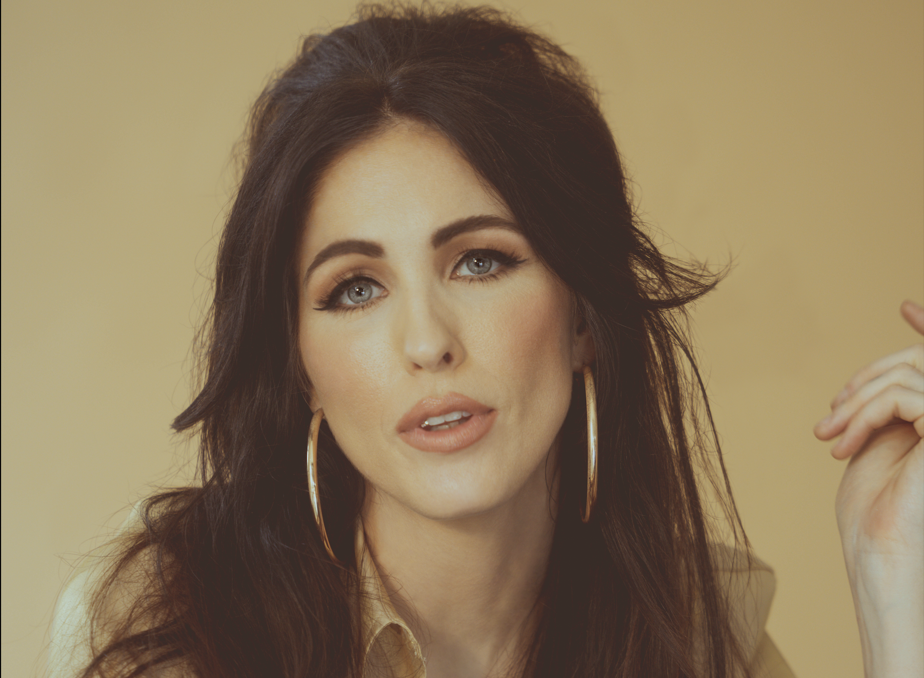 brunette woman wearing '60s makeup and hoop earrings