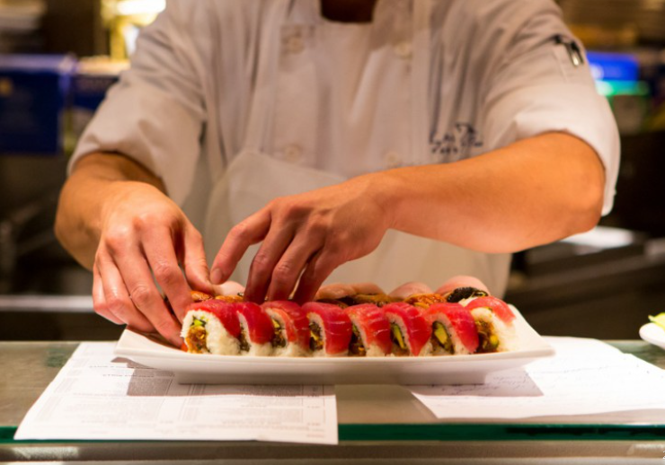 chef's hands preparing sushi roll