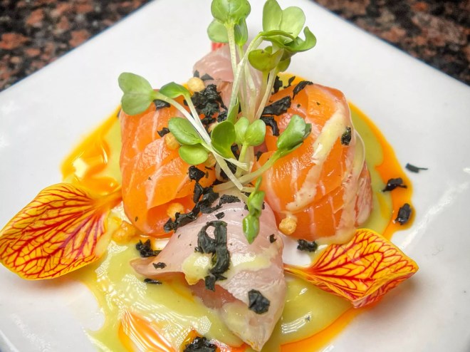 raw fish with colorful garnishes on a plate