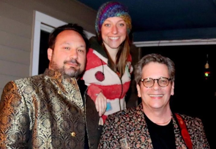 two men and a woman smile for the camera