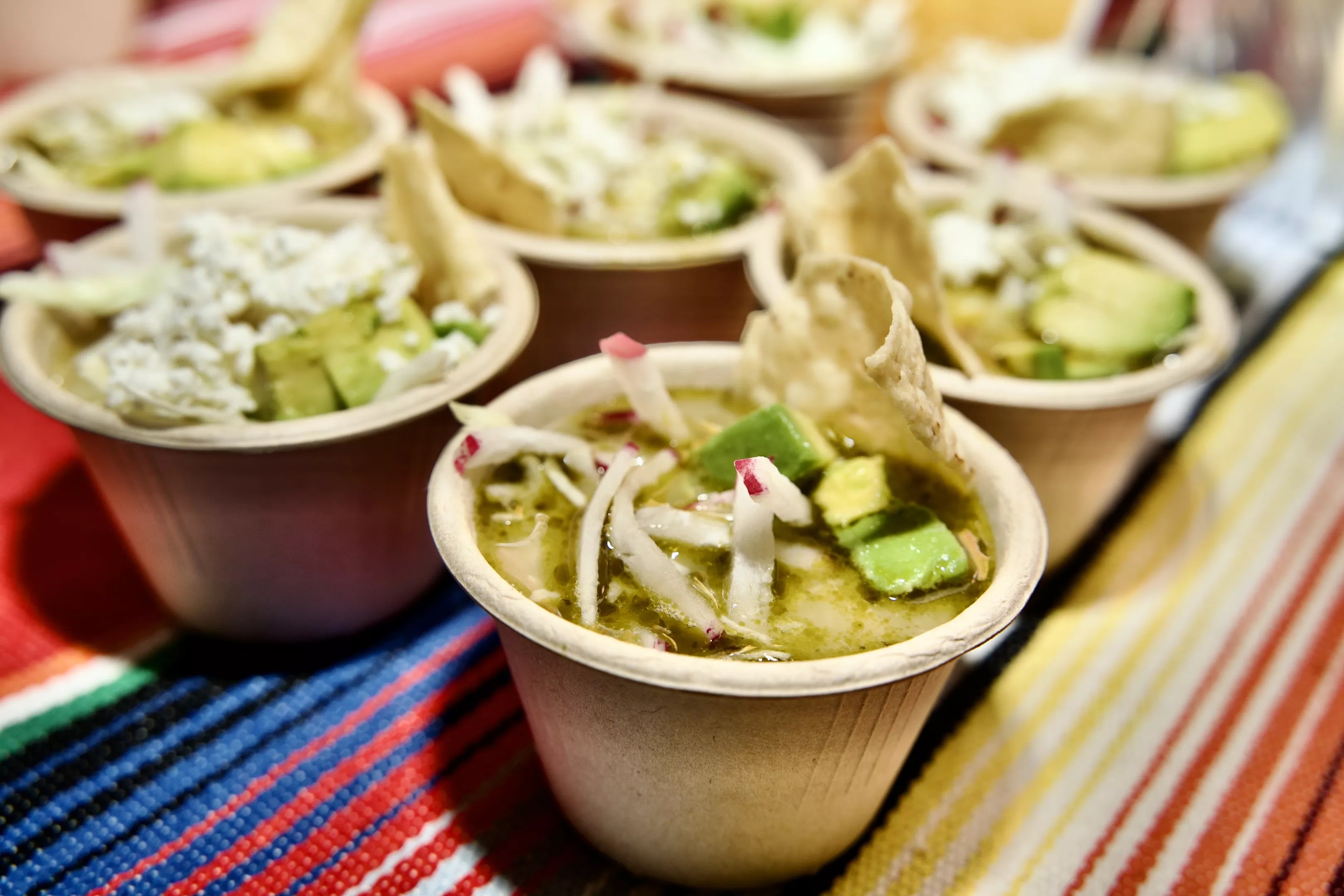 small cups of pozole on a colorful tablecloth