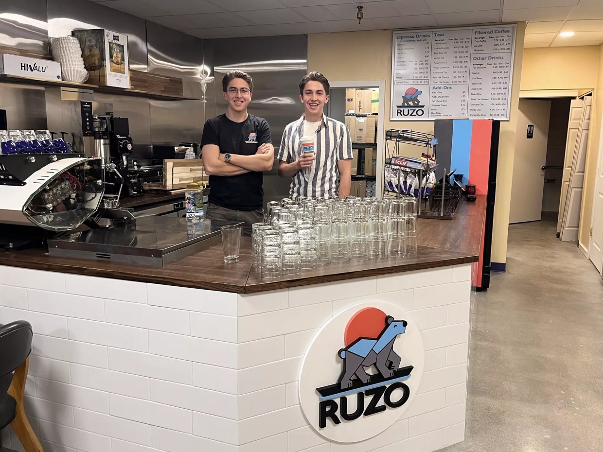 Two men standing behind a coffee shop counter