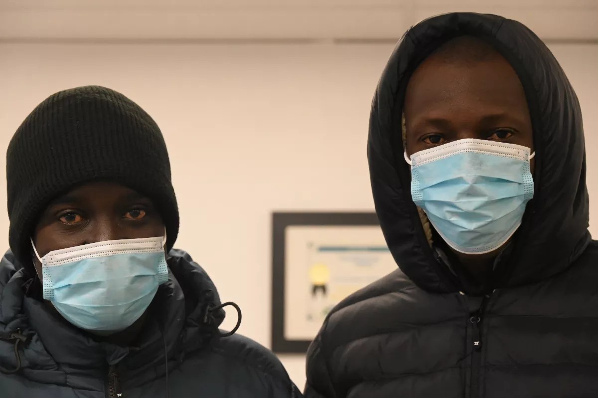 Two Mauritanian migrants stand with masks on.