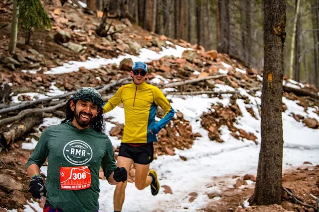 Men run happily down a snow-covered trail