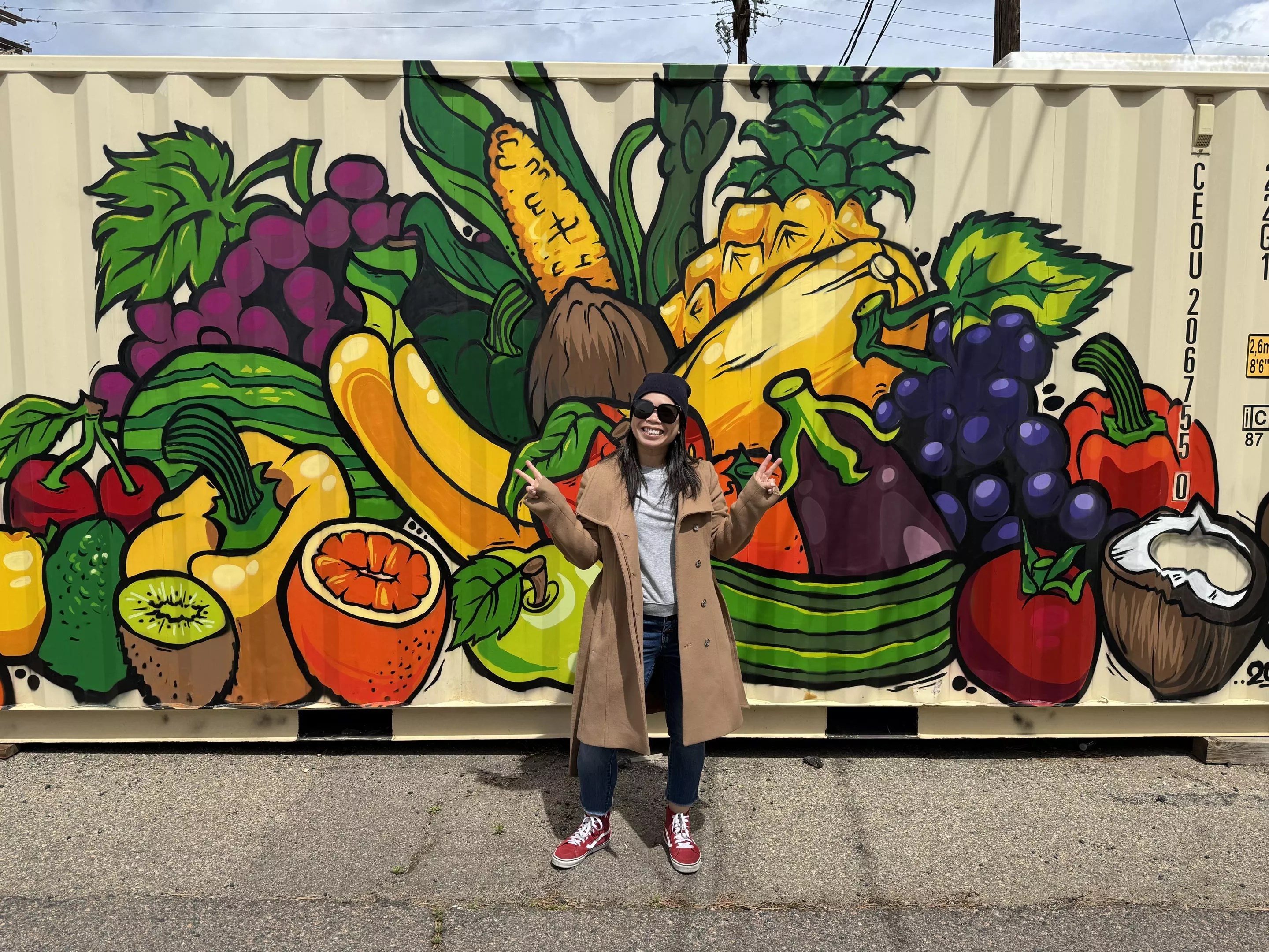 woman in glasses in front of mural.