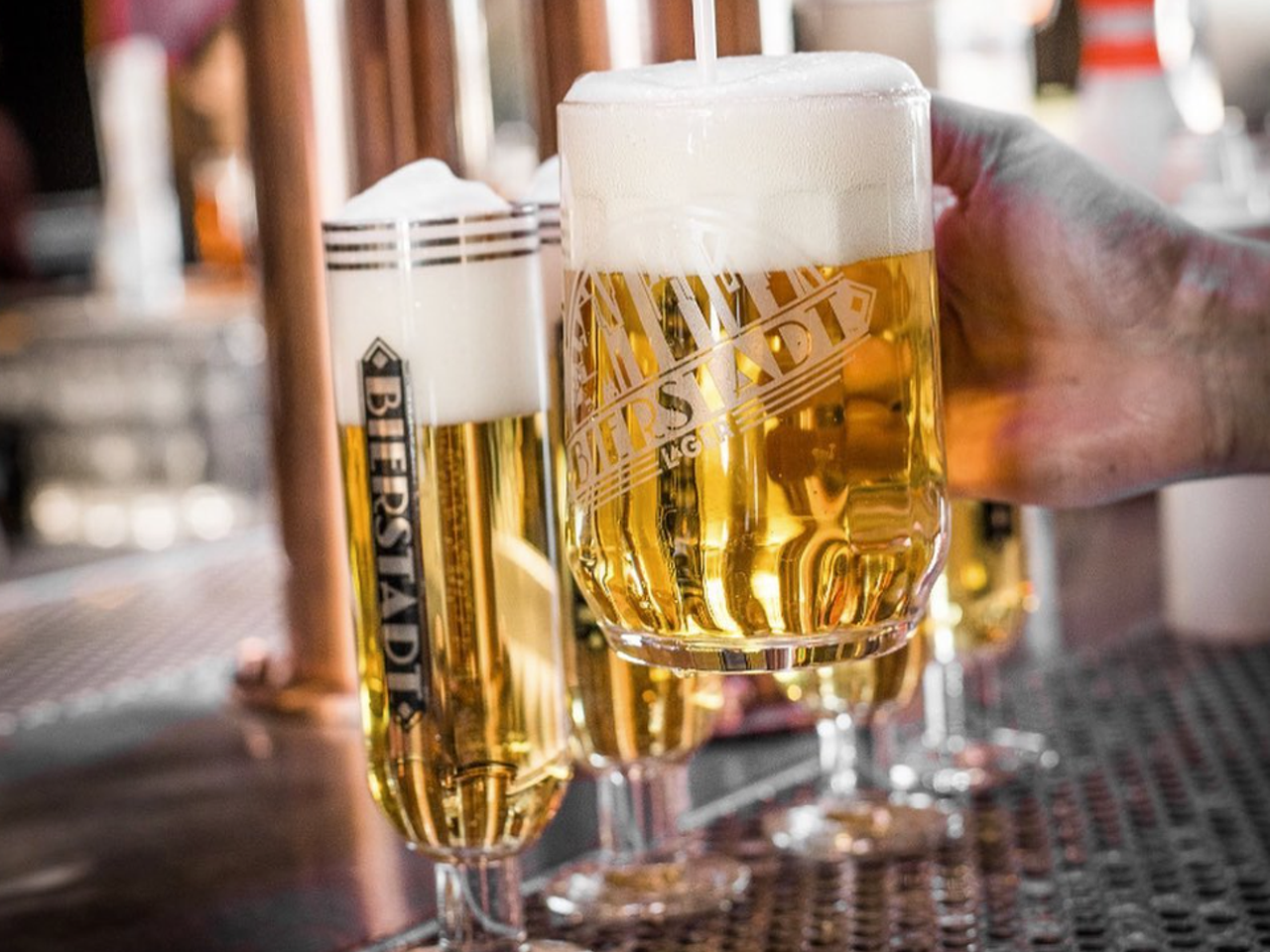 two beers in glasses in front of taps
