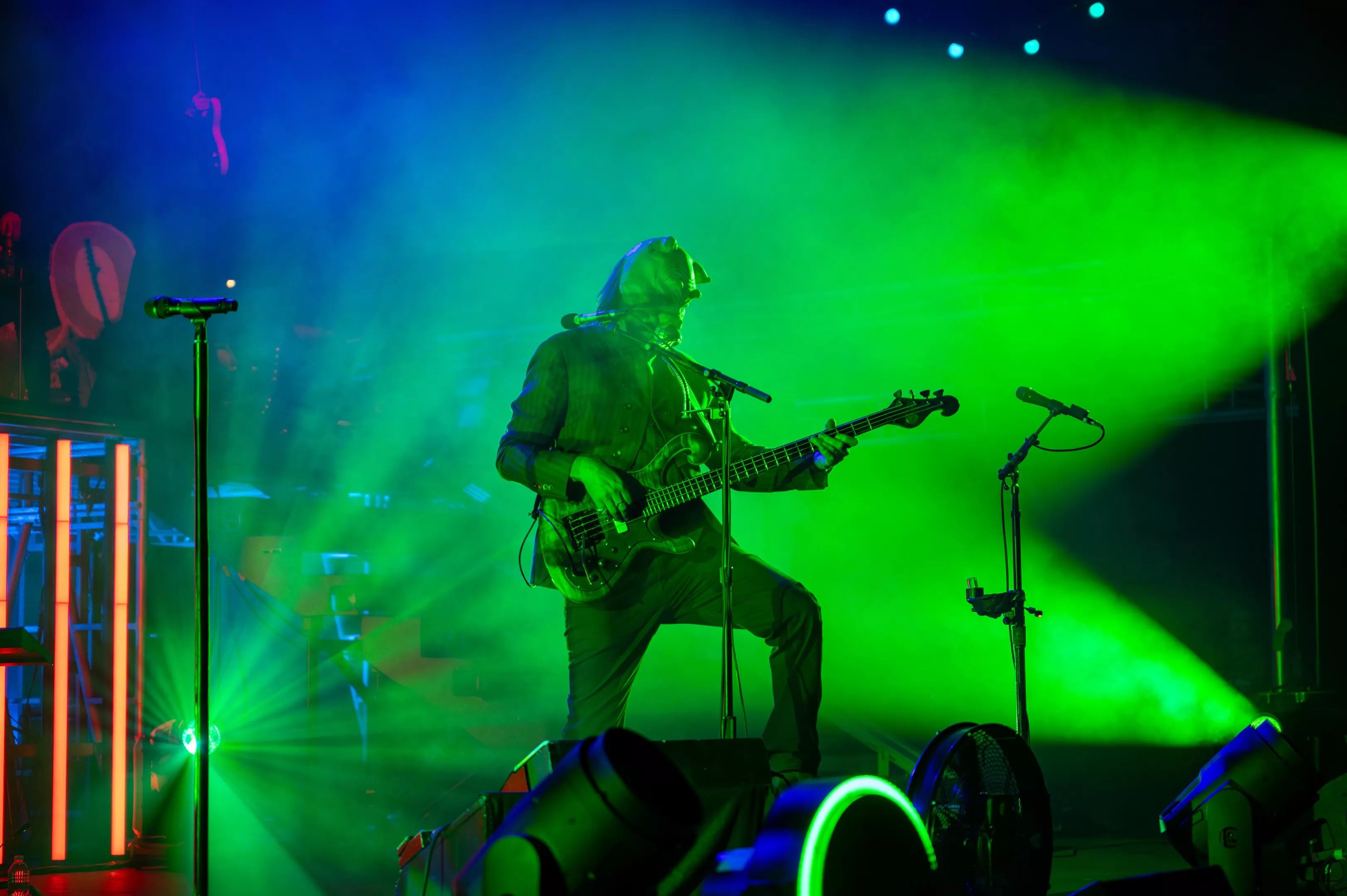 man in a mask playing guitar in green lights