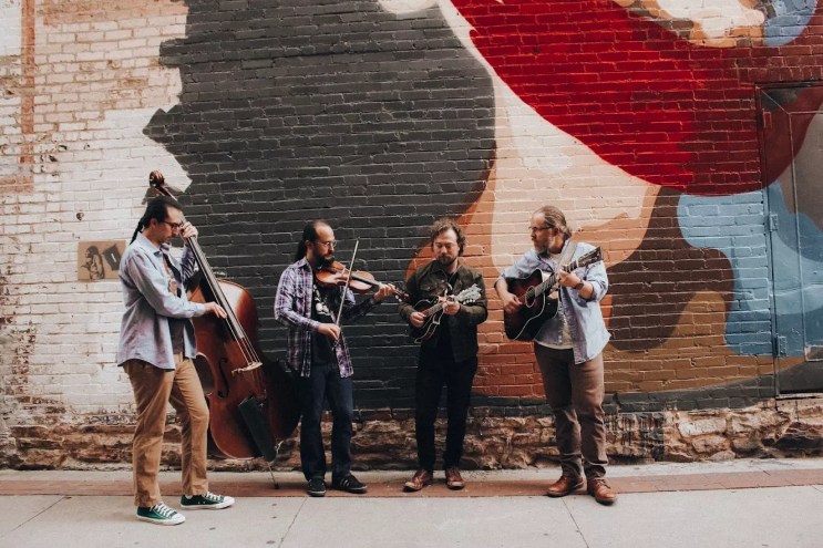 bluegrass band performing in front of a mural