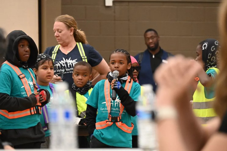 Child holds microphone and talks in public.
