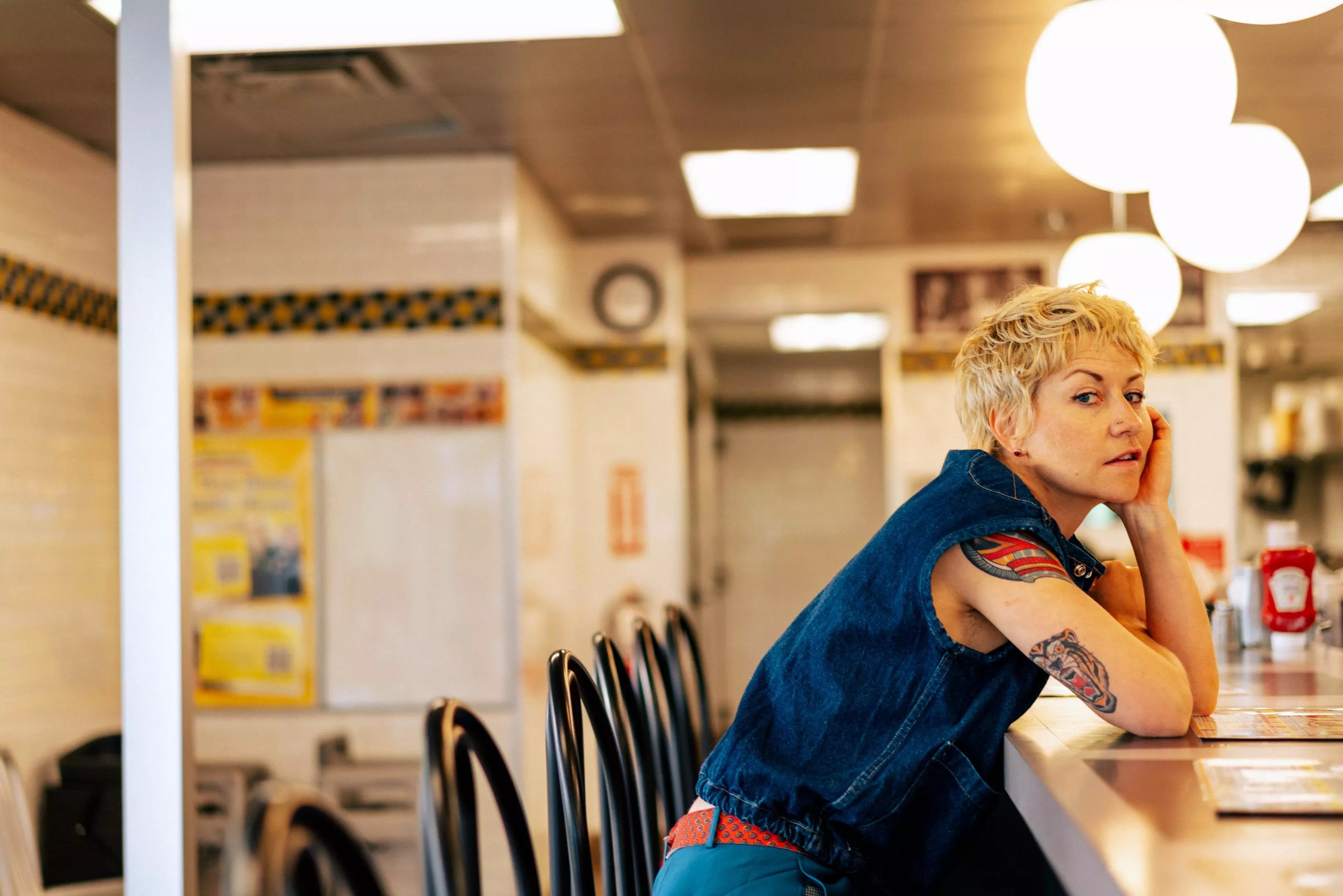 woman with pixie cut leans on diner bar