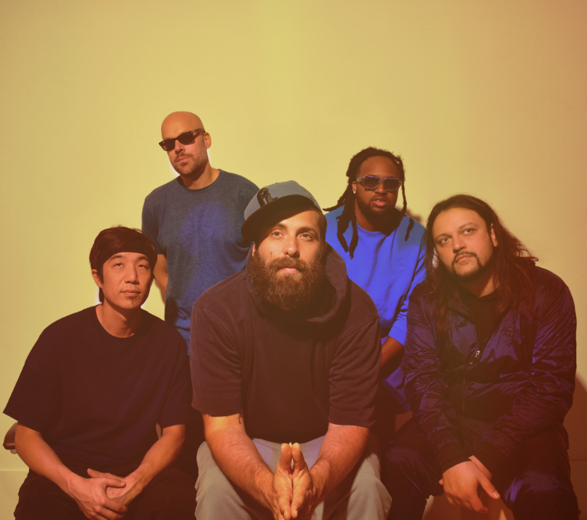 five men pose against a yellow wall