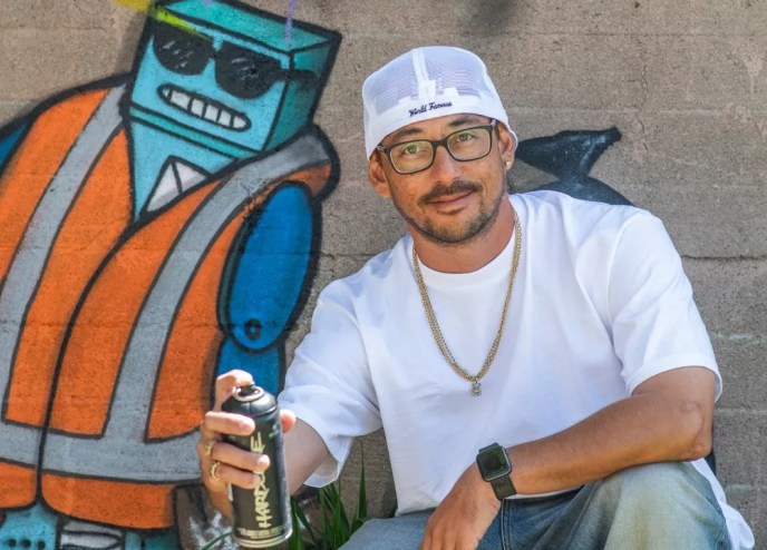 man in hat with spraypaint against mural