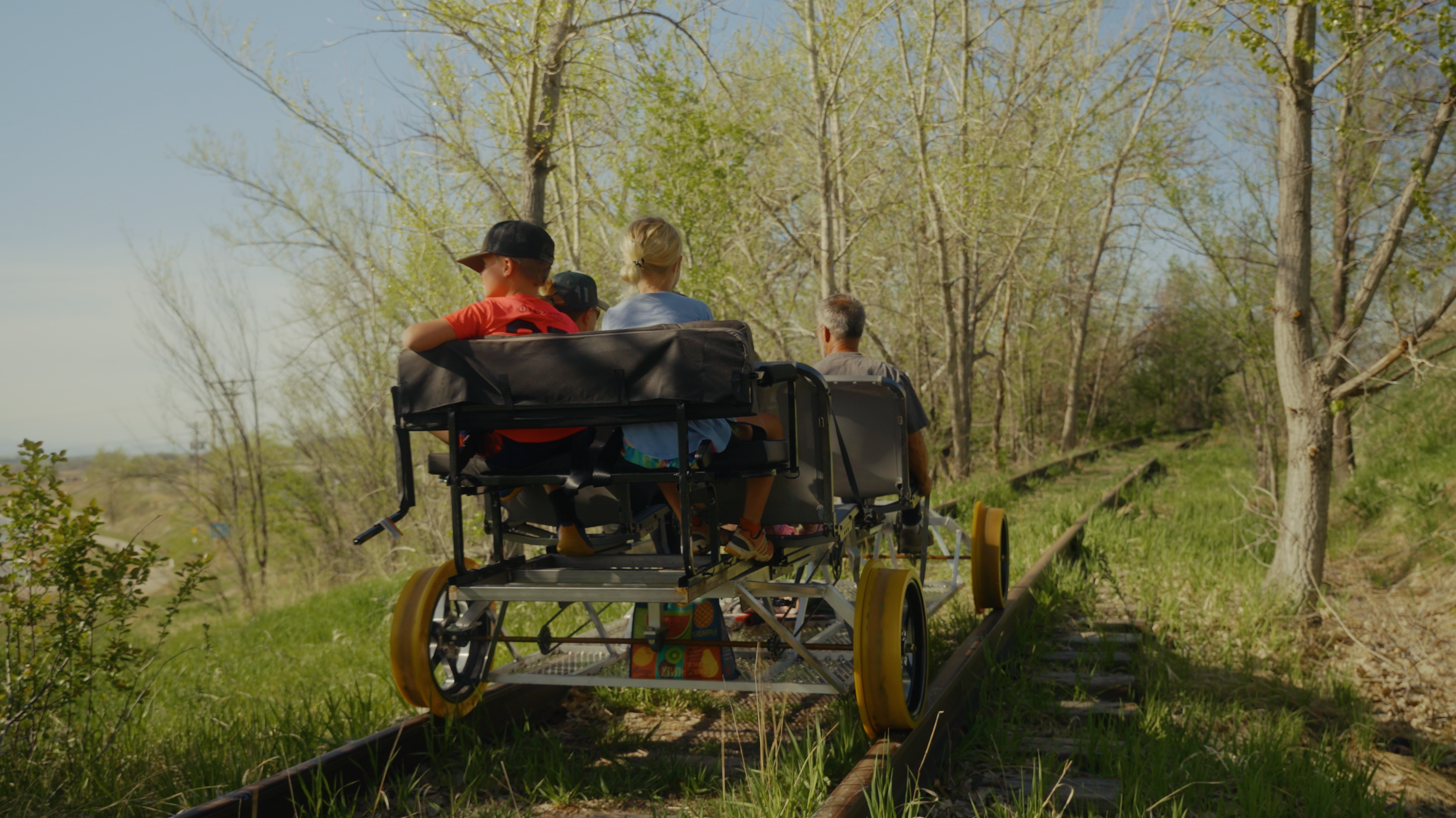 A family pedaling a railbike through a forested stretch in Erie, Colorado