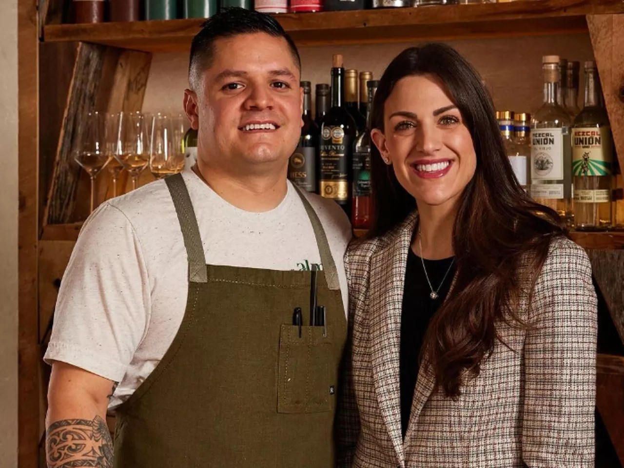 man in a apron next to a woman in a blazer