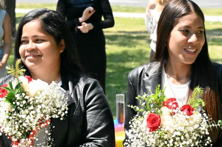 Two women hold flowers.