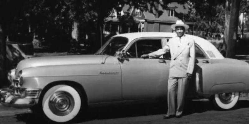 vintage photo of a man standing by a car