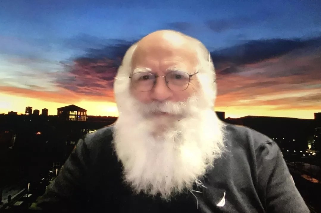 John Wren sitting in front of a sunset background.