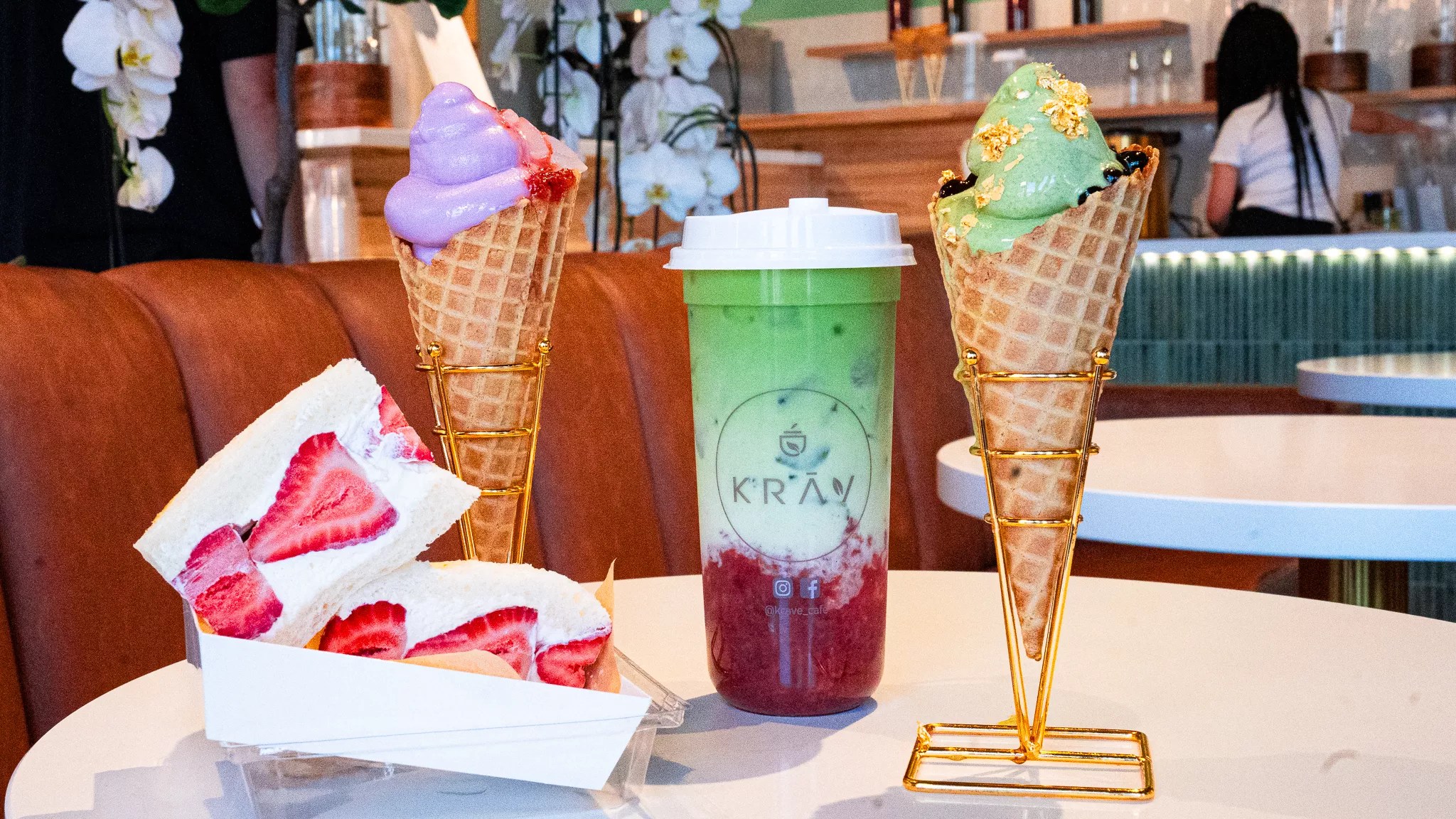 two waffle cones, a strawberry and cream sandwich and a boba drink