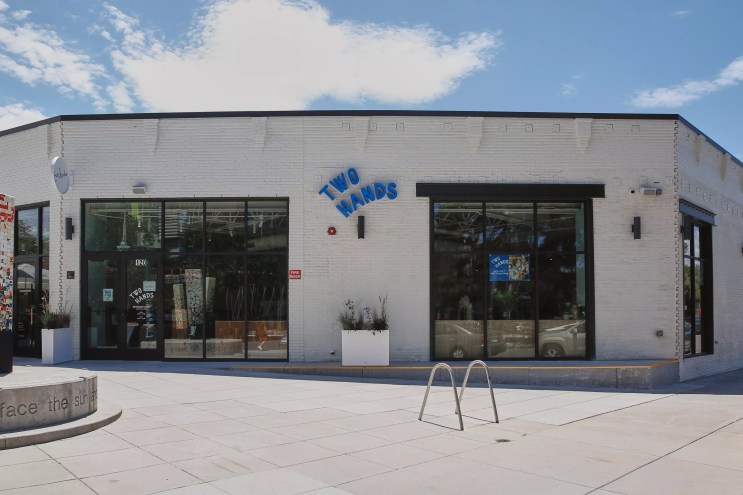 exterior of a white building with a blue sign that says "two hands"
