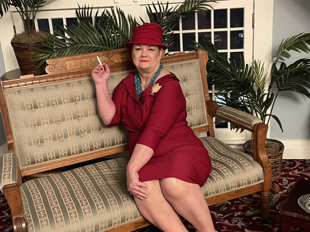 woma in maroon dress and hat on sofa