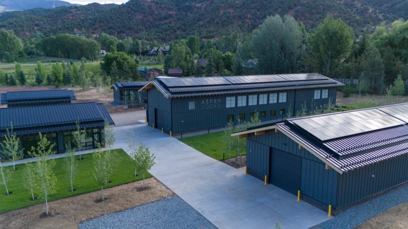 several long, narrow buildings in front of hills and trees