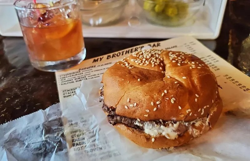 burger on wax paper with menu and drink.
