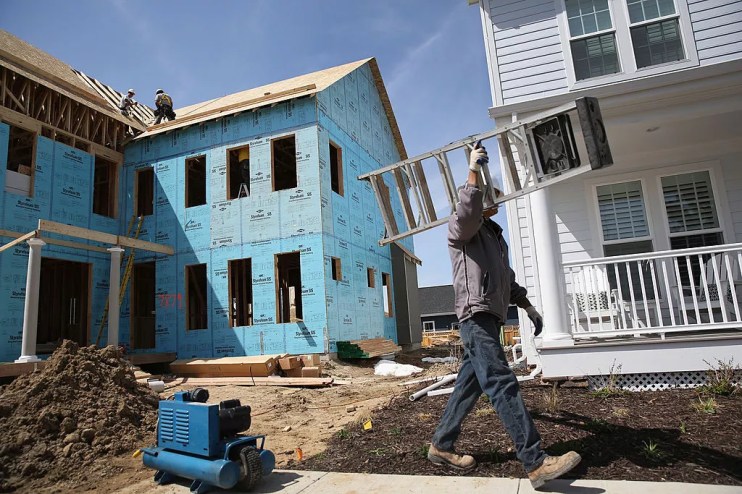 worker with ladder walking by house construction