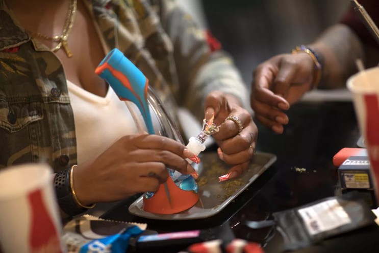 Woman loads bong bowl with marijuana