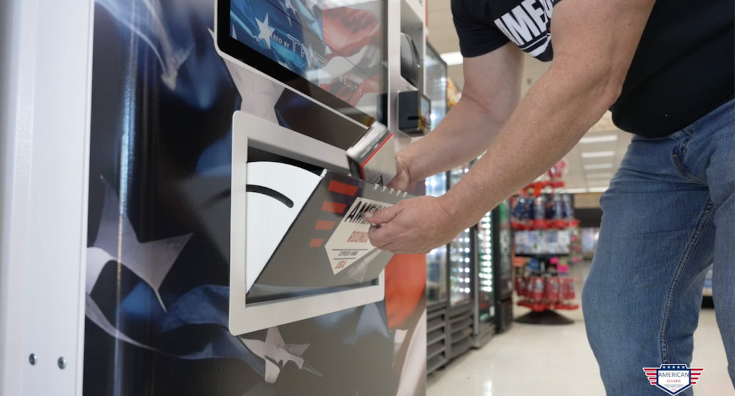 A man takes ammo from a vending machine.