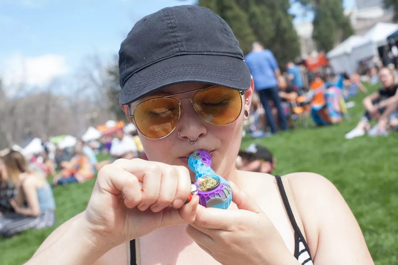 Woman smokes marijuana out of pipe at park