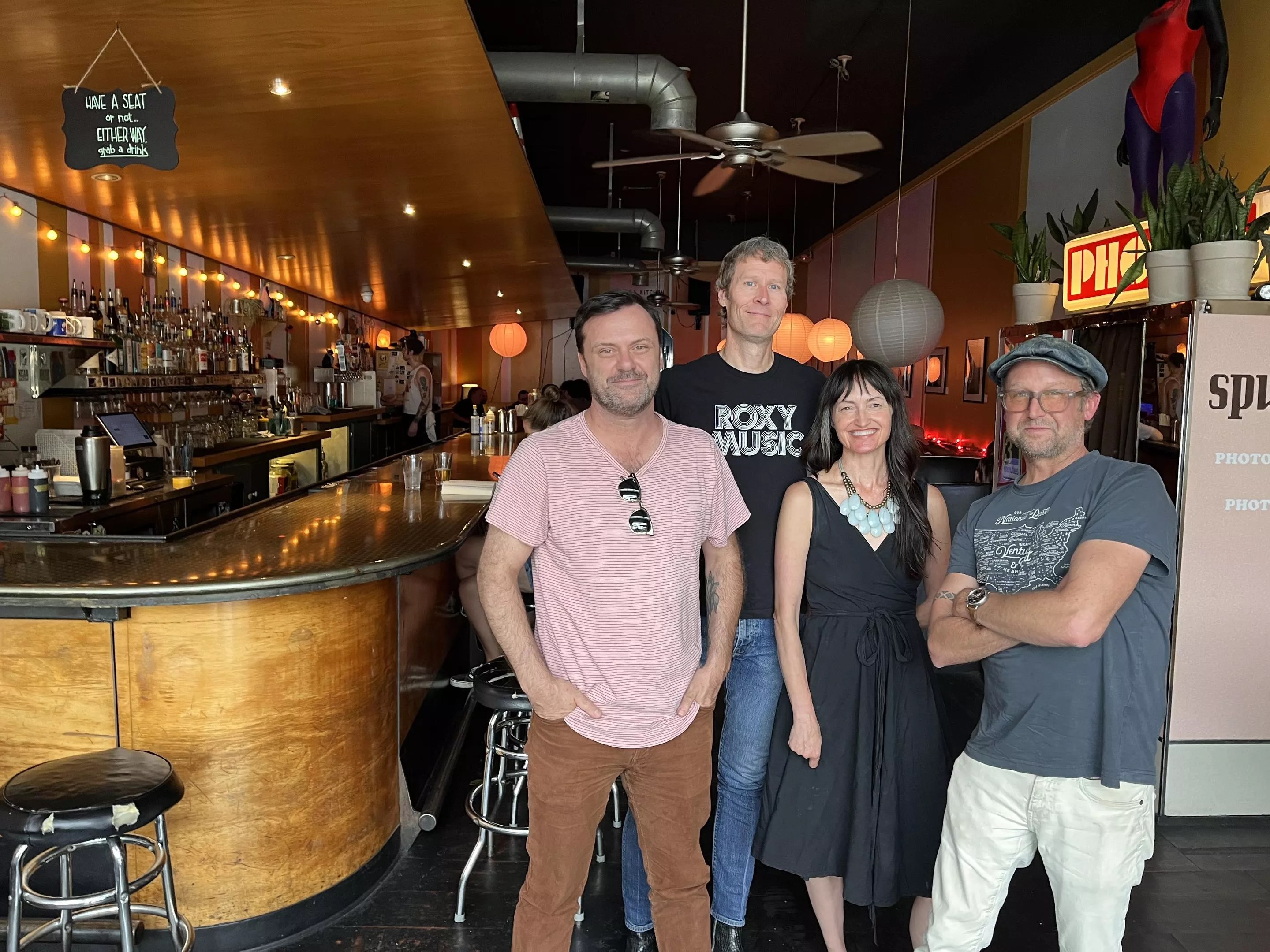 four people posing for a photo inside a bar