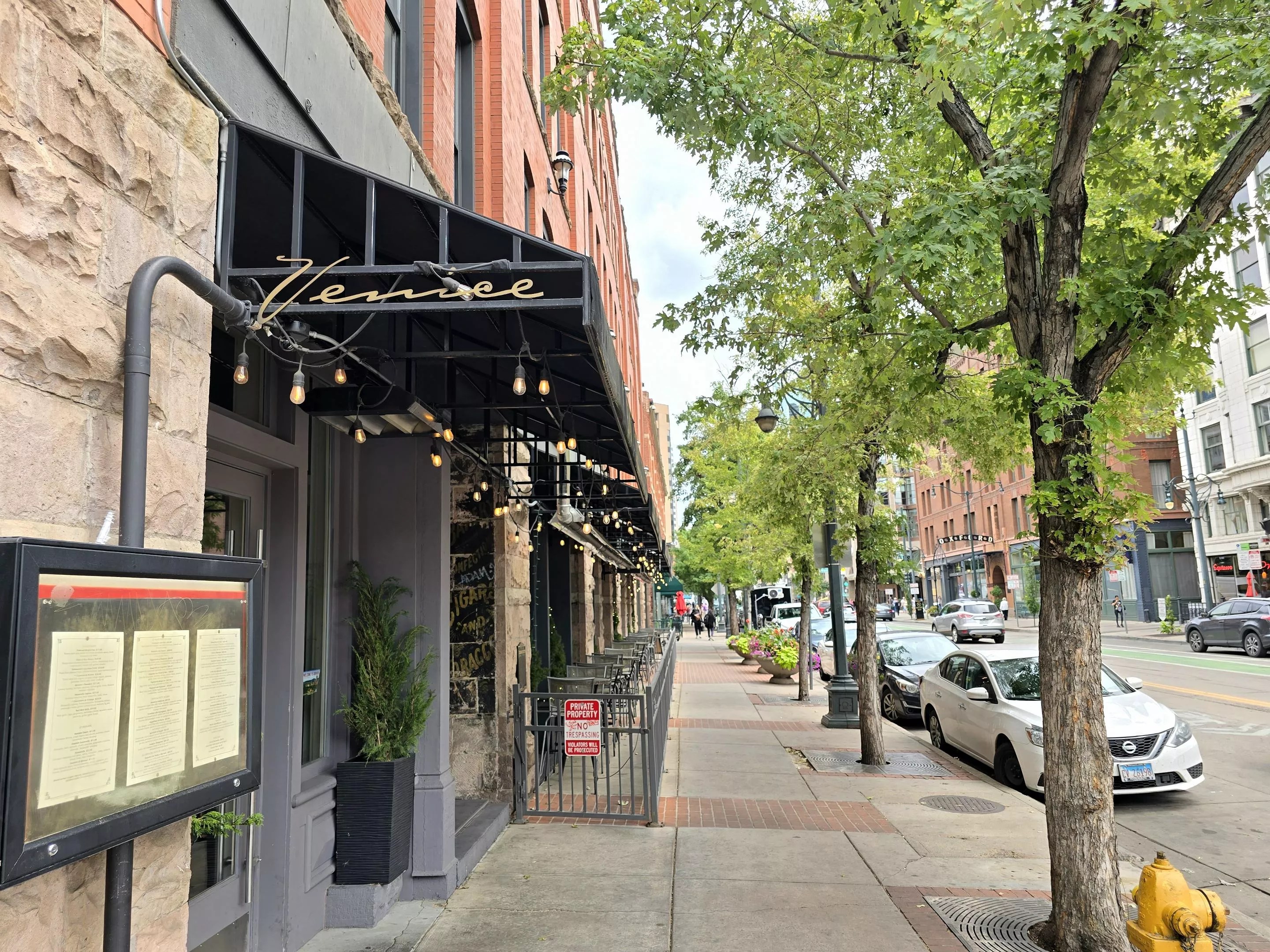 black awning on building next to a sidewalk lined with trees
