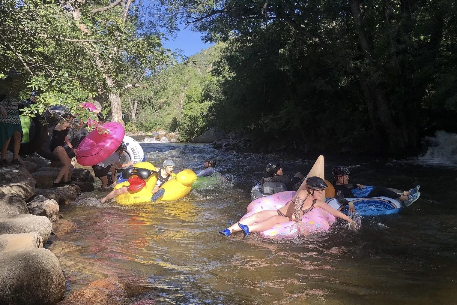Several people with colorful tubes entering Boulder Creek