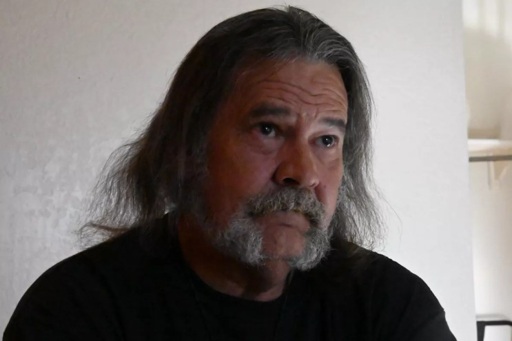 Man with long hair and beard gives interview